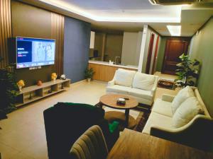 a living room with two couches and a flat screen tv at Gold Crest, One bed Suite in Lahore