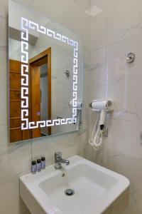 uma casa de banho com um lavatório branco e um espelho. em Hotel Billy em Himare