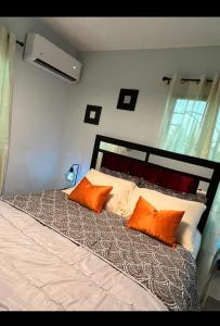 sypialnia z łóżkiem z pomarańczowymi poduszkami w obiekcie E & J Lifestyle w mieście Río San Juan