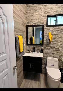 a bathroom with a sink and a toilet and a mirror at E & J Lifestyle in Río San Juan