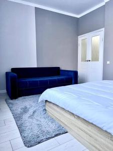 1 dormitorio con sofá azul y cama en Expo New Life 4, en Prigorodnyy