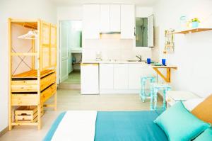 una pequeña cocina con armarios blancos y una cama en una habitación en La Casita Surf en Famara