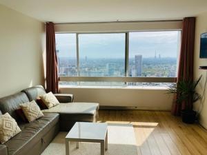 uma sala de estar com um sofá e uma grande janela em Logement cosy-chic Paris La Défense em Puteaux