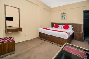 a bedroom with a bed with red pillows and a mirror at OYO Hill Grand Himalaya in Darjeeling