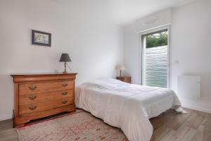 een slaapkamer met een bed, een dressoir en een raam bij Confort et modernité dans cette jolie maison in Le Pouliguen
