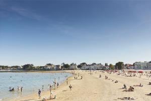 Un grupo de personas en una playa en el agua. en Le Pouliguen - Maison lumineuse avec jardin, en Le Pouliguen