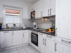 eine weiße Küche mit weißen Schränken und einer Spüle in der Unterkunft Holiday Home Backbord by Interhome in Norddeich