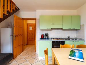 a kitchen with green cabinets and a table with a laptop at Apartment Dromaè-2 by Interhome in Mezzolago