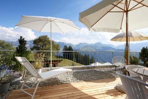 a patio with chairs and umbrellas on a deck at Gantrisch Lodge Ottenleuebad in Guggisberg