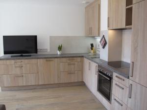 a kitchen with wooden cabinets and a flat screen tv at Apartment Spieglhof-1 by Interhome in Sarntal