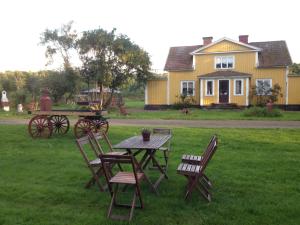 a picnic table and chairs in front of a yellow house at Marielund Gård in Skara