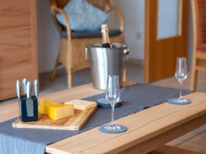 ノルトダイヒにあるApartment Kluntje by Interhomeのグラス2つとチーズ、そしてシャンパンのボトルが置かれたテーブル