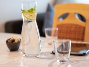 een glazen vaas met een citroen op een tafel met twee glazen bij Apartment Kluntje by Interhome in Norddeich