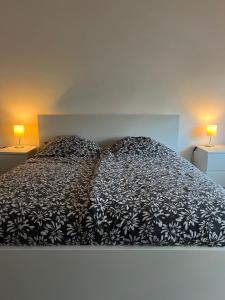 1 cama con edredón blanco y negro y 2 lámparas en Apartments im Herzen von Velbert, en Velbert