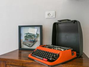 サン・ジミニャーノにあるApartment Casa Renai a San Gimignano-3 by Interhomeの絵の横に座るオレンジのタイプライター