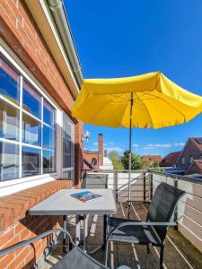 a yellow umbrella and a table and chairs on a balcony at Dörte in Greetsiel