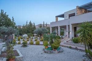 a garden in front of a house with trees and plants at Physis Luxury Villa in Archangelos