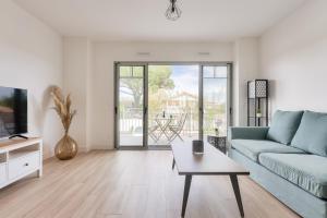 Una sala de estar con un sofá azul y una mesa. en À 500m de la plage de la Jetée, appartement pour 4, en Andernos-les-Bains