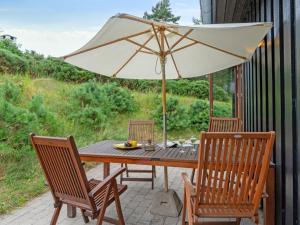 a wooden table with an umbrella on a patio at Holiday Home Jonce - 250m from the sea in Sealand by Interhome in Vejby