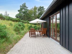 a patio with a table with an umbrella and chairs at Holiday Home Jonce - 250m from the sea in Sealand by Interhome in Vejby