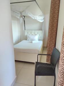 a small bedroom with a bed and a chair at Garden Courts Hotel Masaka in Masaka