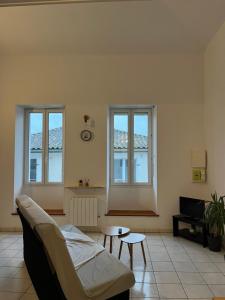 een woonkamer met een bank en twee ramen bij Joli appartement in Cozes