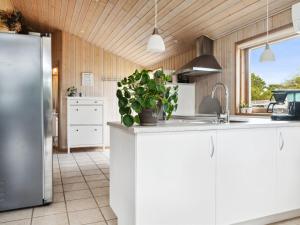 cocina con armarios blancos y nevera de acero inoxidable en Holiday Home Dagna - 400m from the sea in Lolland- Falster and Mon by Interhome en Rødby