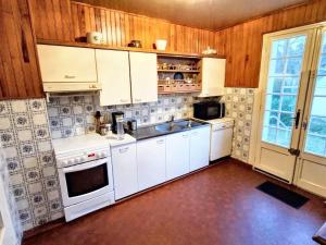 een keuken met witte apparatuur en houten wanden bij Maison de 6 chambres avec jardin amenage a Donville les Bains a 1 km de la plage in Donville-les-Bains