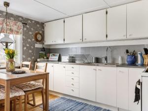 une cuisine avec des placards blancs et une table en bois dans l'établissement Holiday Home Skjutsmåla - B, à Olofström