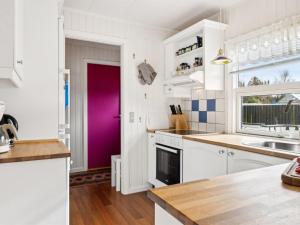cocina con armarios blancos y puerta morada en Holiday Home Senja - 450m from the sea in NE Jutland by Interhome, en Hals