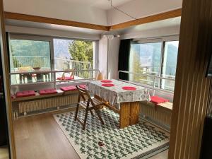 um quarto com uma mesa e uma varanda com janelas em Bellavista Marilleva 1400 - Val di Sole em Marilleva