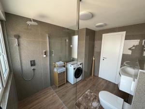 a bathroom with a shower and a washing machine and a toilet at Panorama Penthouse Punat in Punat +50 photos