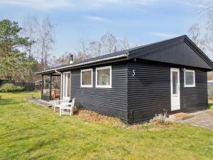 una casa negra con una silla en un patio en Holiday Home Josef - 1-4km from the sea in Sealand by Interhome en Rørvig