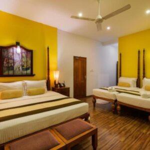 Suneetha Hotel في بولوناروا: غرفة نوم بسريرين وجدران صفراء