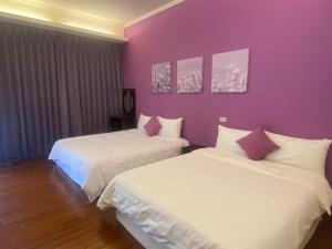 duas camas num quarto com paredes roxas em Chin Shue B&B em Guanshan