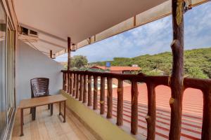 a balcony with a wooden bench and a large window at The Greenpark Retreat, Mahabaleshwar in Mahabaleshwar