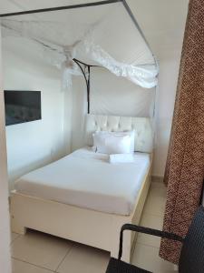 een slaapkamer met een wit bed en een baldakijn bij Garden Courts Hotel Masaka in Masaka