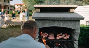 Ein Mann kocht Essen im Außenofen. in der Unterkunft Villaggio Mietta in Castiglioncello