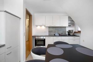 a kitchen with white cabinets and a table and chairs at Zäh in Meckenbeuren