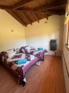 2 Betten in einem Zimmer mit einem TV an der Wand in der Unterkunft Cabaña Cordón Situación in Trevelín