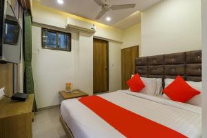 ein Schlafzimmer mit einem großen Bett mit roten Kissen in der Unterkunft OYO Hotel Shubham Inn in Ahmedabad