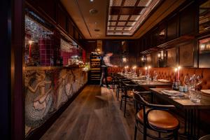 a restaurant with tables and chairs and a man in the background at TORTUE HAMBURG - Schöner als die Fantasie in Hamburg