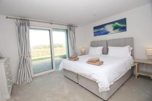 um quarto com uma cama grande e uma janela grande em Coastal apartment sea views em Saint Merryn