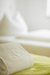 a white towel sitting on top of a bed at Hotel am Wittelsbacher Markt by greenpartment in Langquaid