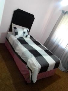 a bed with a black and white checkered blanket at M&T Guesthouse in Orkney