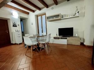 ein Wohnzimmer mit einem Tisch, Stühlen und einem TV in der Unterkunft La Corte di Suna in Verbania