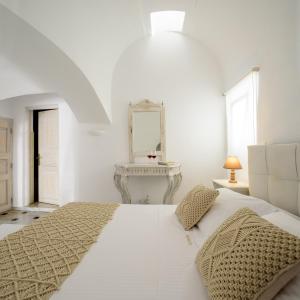 Dormitorio blanco con cama blanca y espejo en MyBoZer Hotel Kallisto, en Imerovigli