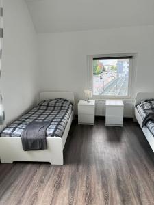 1 dormitorio con 2 camas, 2 mesas y una ventana en Apartments im Herzen von Velbert, en Velbert