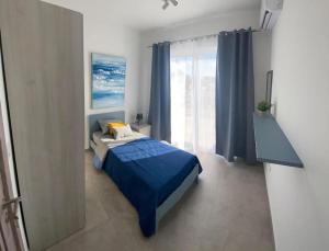 una camera con un letto blu e una grande finestra di Yellow Hill Penthouse a Żebbuġ