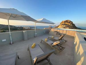 balcone con sedie, ombrelloni e oceano di Yellow Hill Penthouse a Żebbuġ